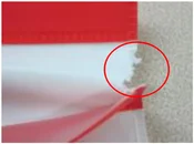 Torn packaging edge. The ellipse identifies a separate tear at the packaging edge.