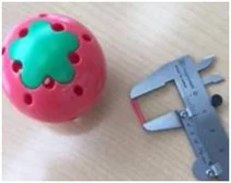 Small part released from a pink ball. The source places this photo under “Internal small parts fall out.” A caliper is shown, but no numerical reading is stated in the slide.