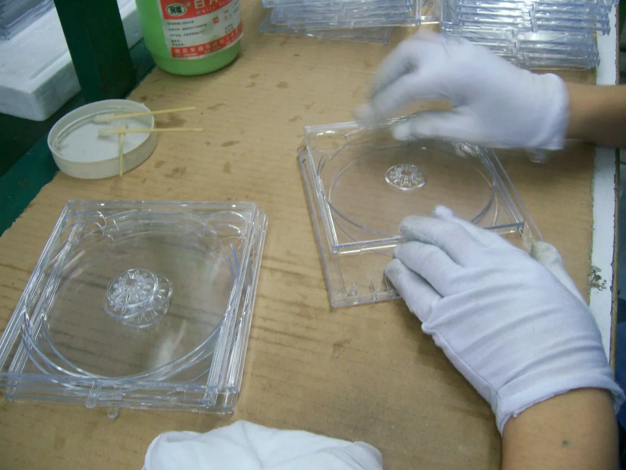 Gloved operator applying lubricant to the sliding rail of a clear internal component